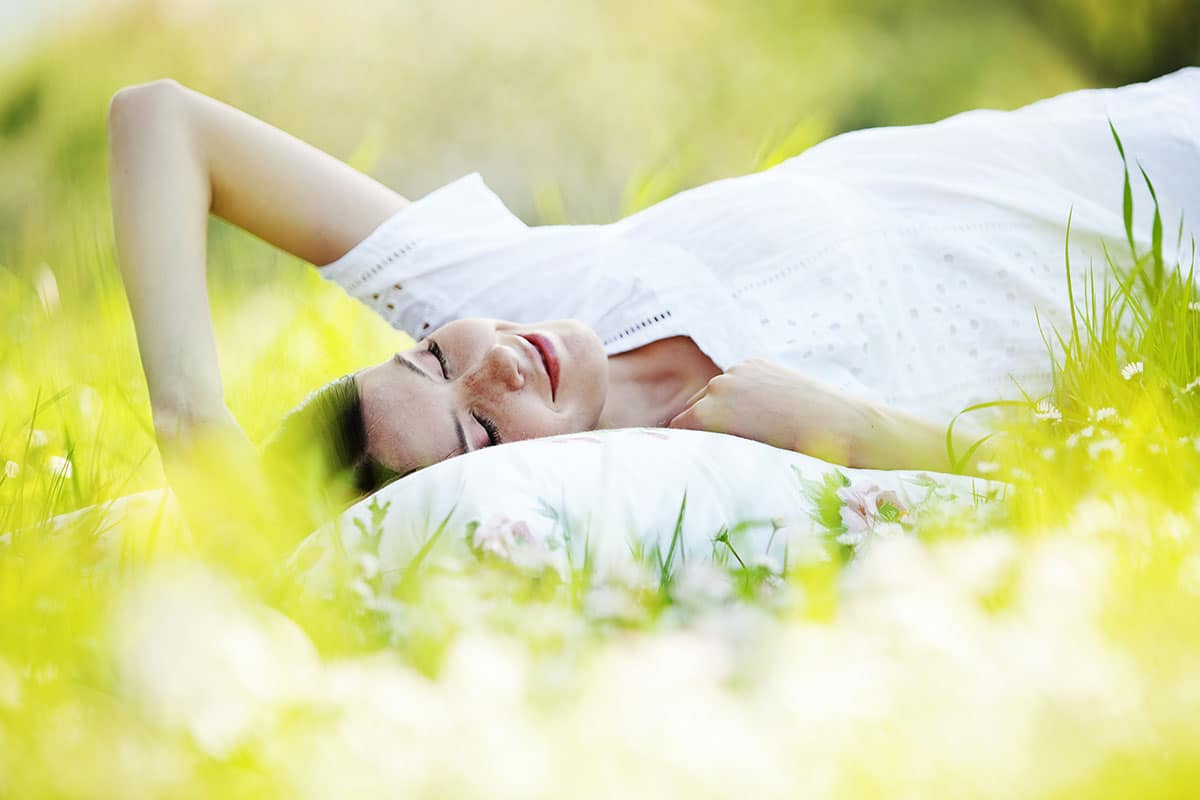 How to Stop Snoring Naturally - Woman lying on grass sleeping.
