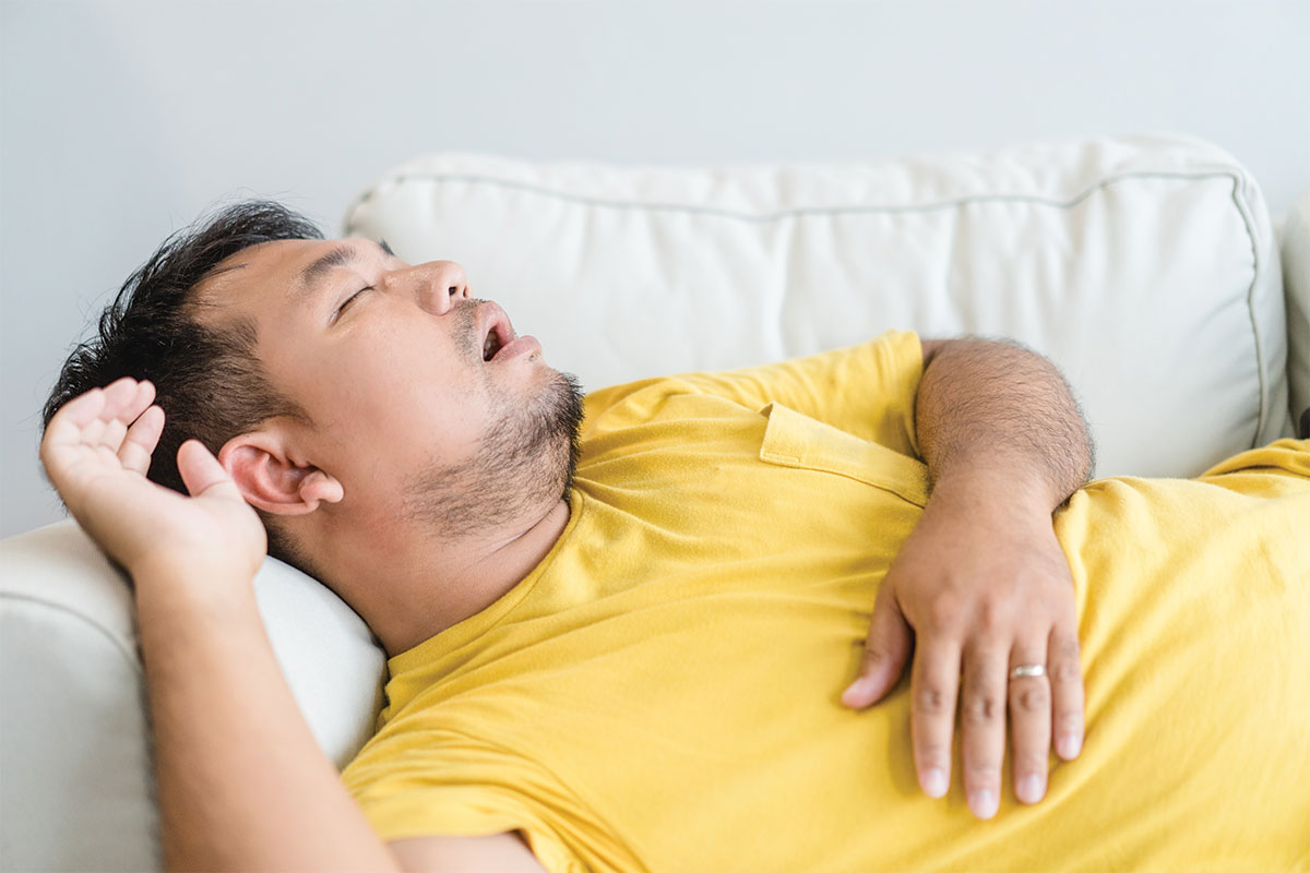 Why do people snore? Man snoring on couch while aslseep.