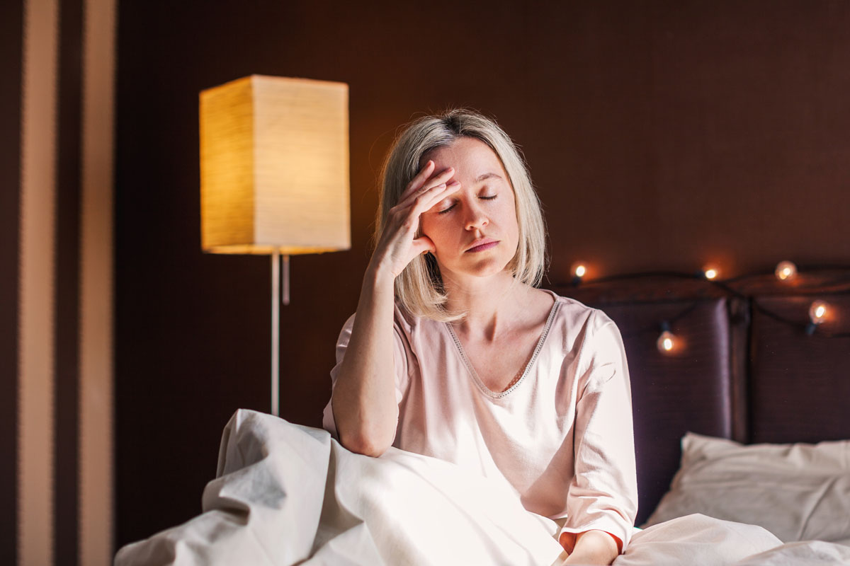 Tired woman in bed affected by snoring and menopause