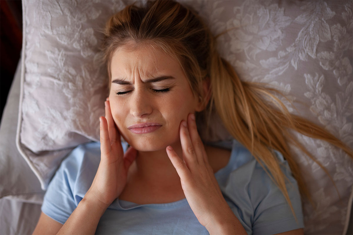 Woman experiencing Bruxism effects in bed.